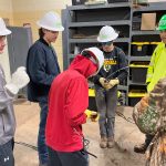High school students wearing hard hats doing an exercise with wires to learn more about Moraine Park's Electricity program.
