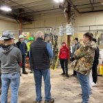 High school students with hard hats standing in a circle and listening to a Moraine Park Gas and Utilities program instructor.