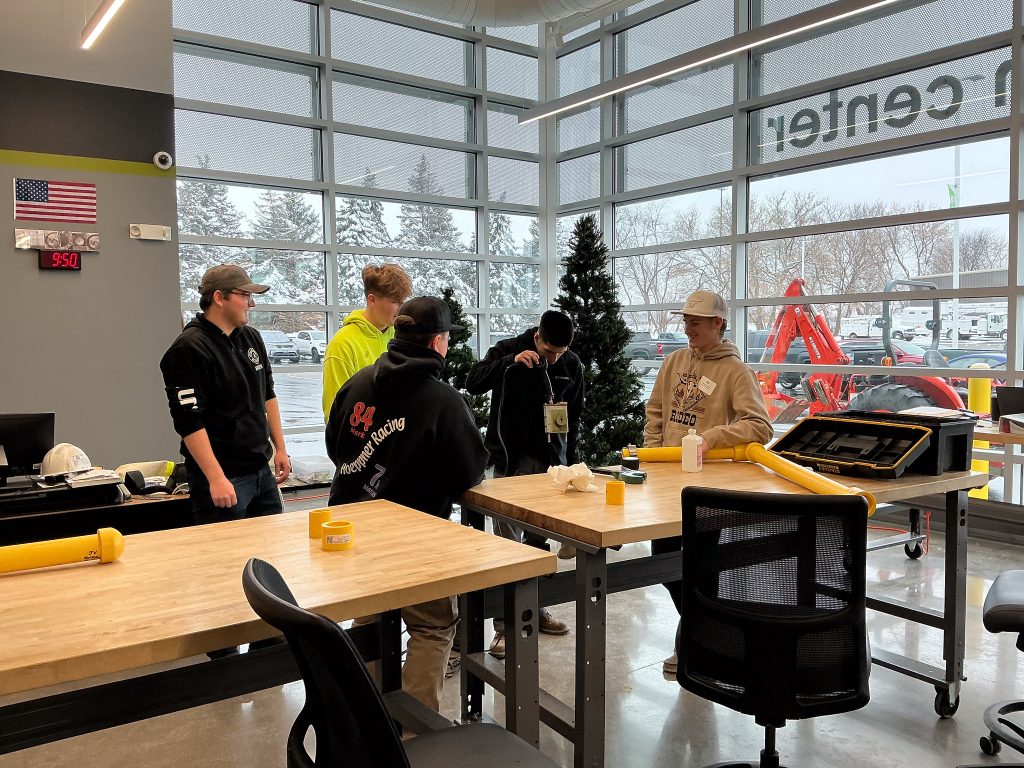 High school students working on on yellow PCP pipes to learn more about the Moraine Park Gas and Utilities program