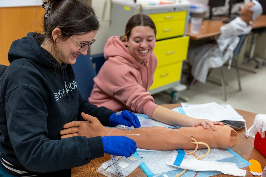 Students working with health care simulators.