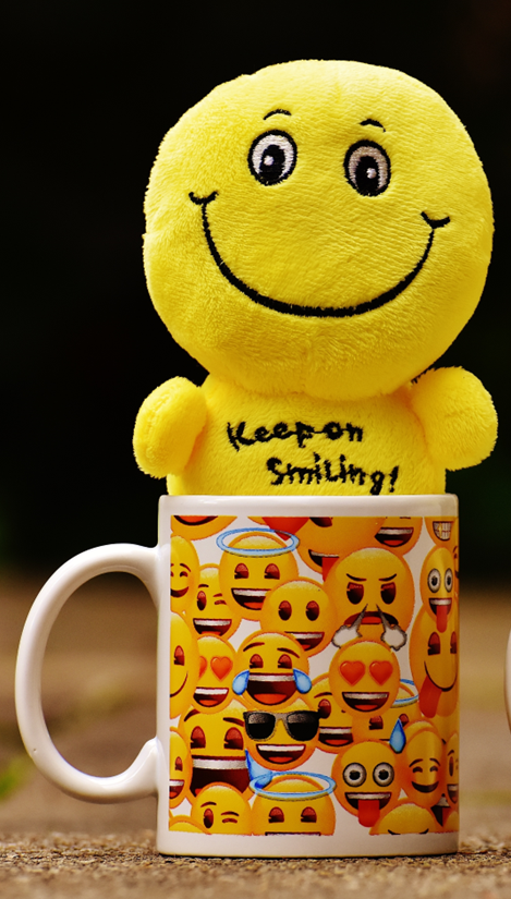 Smiling plush toy in a coffee cup.
