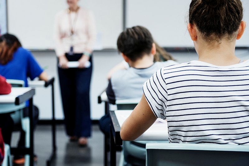 Backs of students in a classroom with instructor in the distance