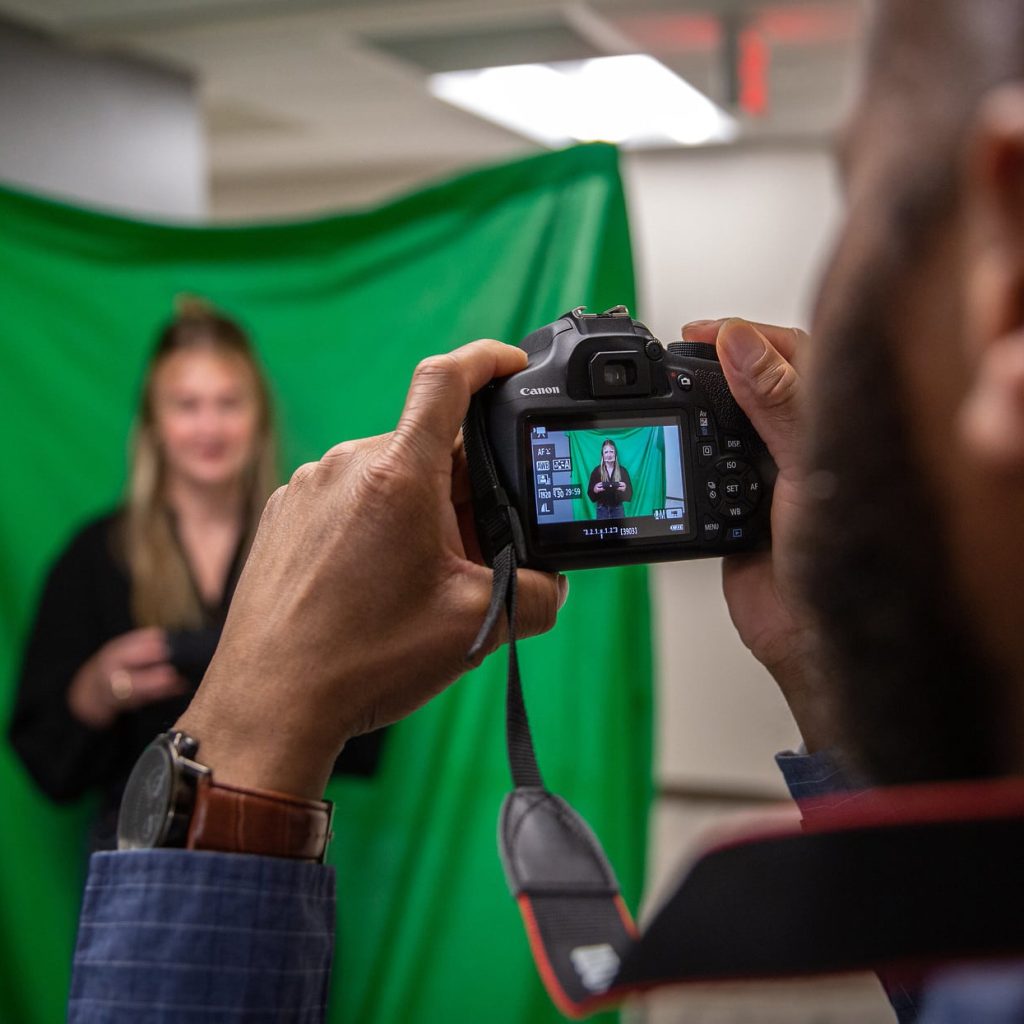 Student holding a camera and taking a photo