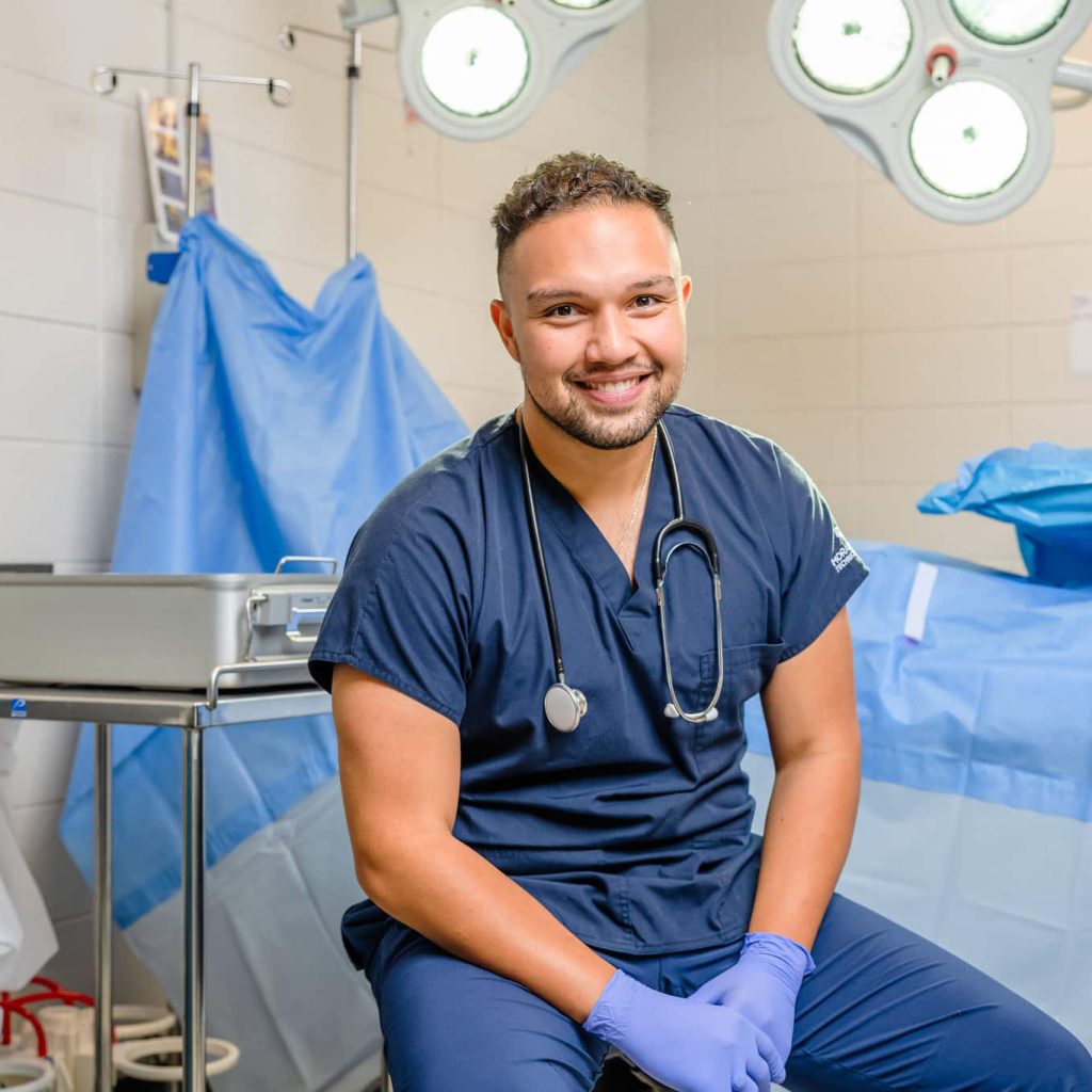 Student in scrubs smiling at the camera