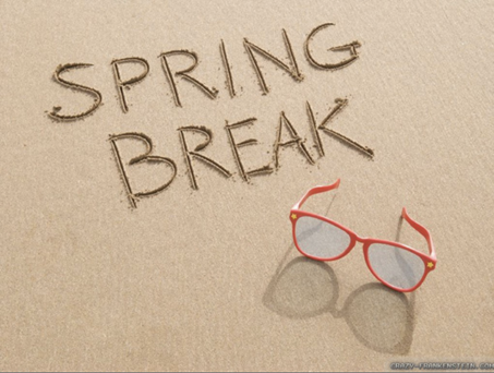 The words Spring Break written in the sand with a pair of red sunglasses sitting below the words