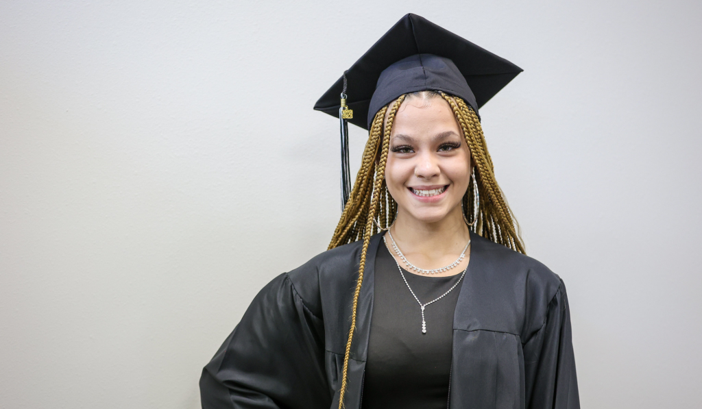 Journey student speaker standing proudly in her cap and gown.