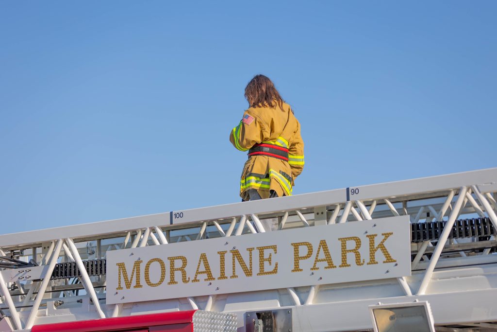 Fire student in gear on fire truck.