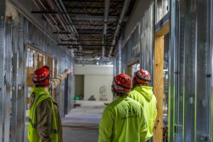 Three construction workers reviewing the worksite for the health and human services wing.