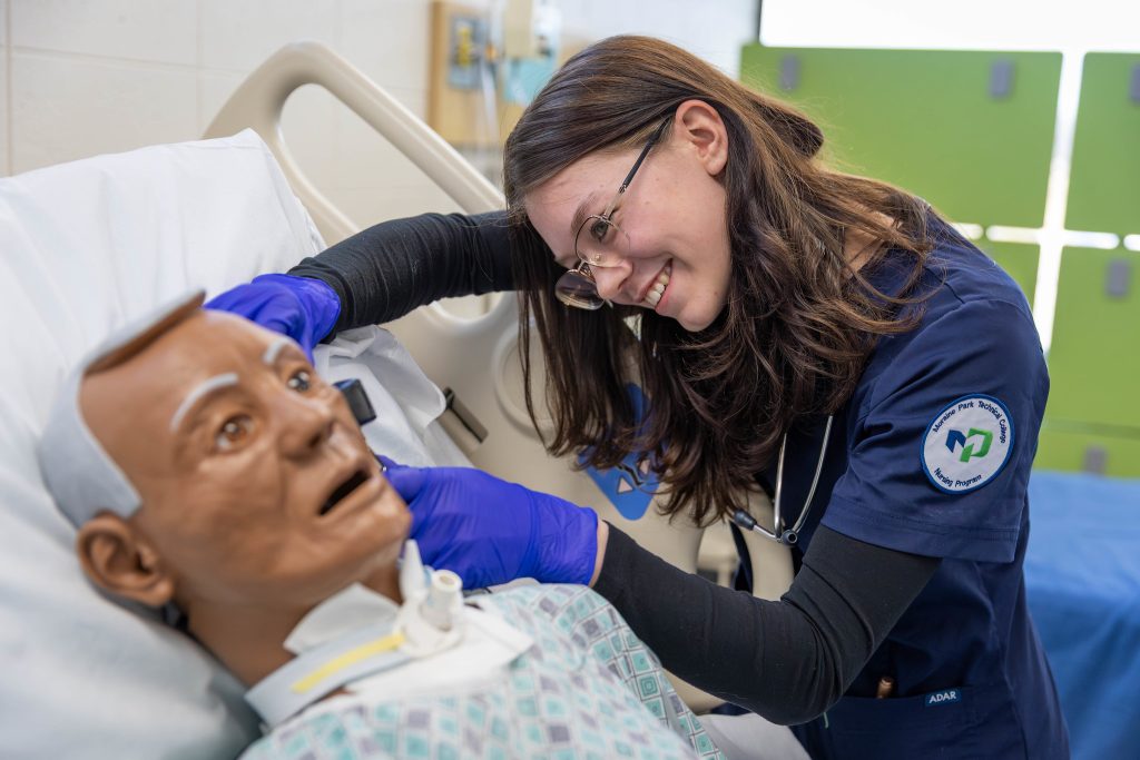 Cynthia Benzel happily practicing her nursing skills on a nursing mannequin.