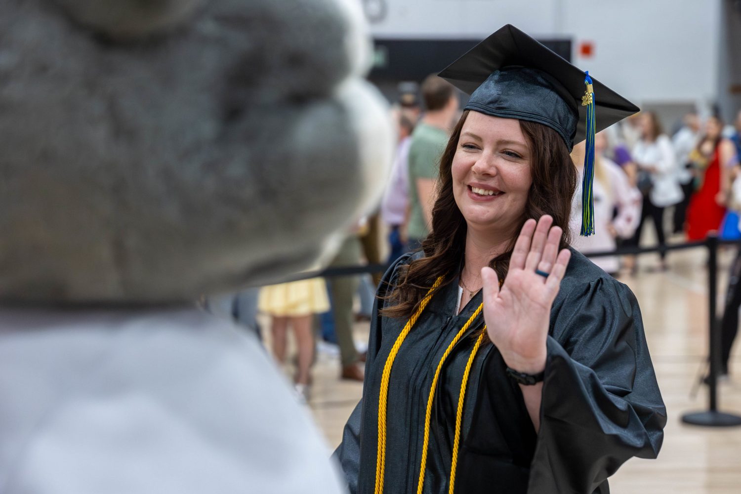 Student in graduation gown high-fiving Maximus, the Moraine Park Technical College mascot.