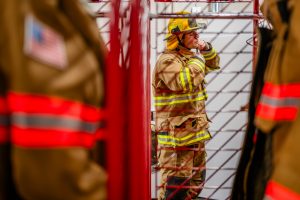 A fire student in full gear strapping on their helmet.