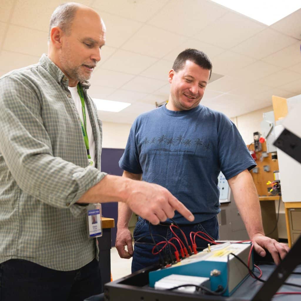 Electricity instructor and student looking at a panel