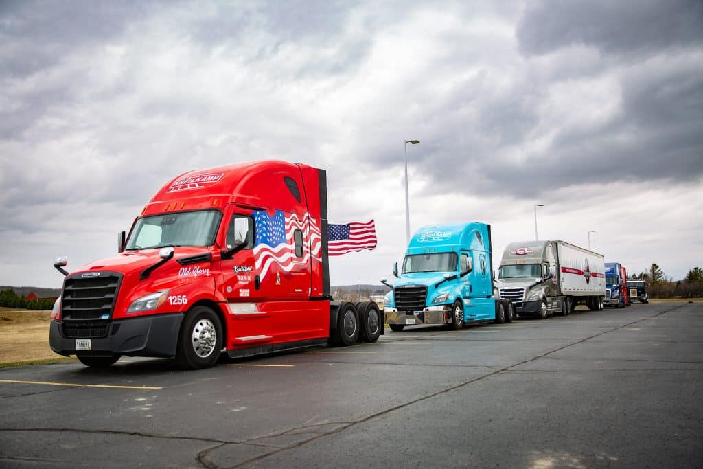 Three majestic trucks parked in front of a US flag,