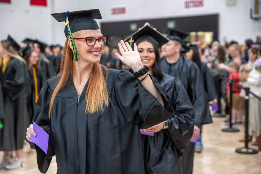 Student smiling and waving at Moraine Park's spring commencement