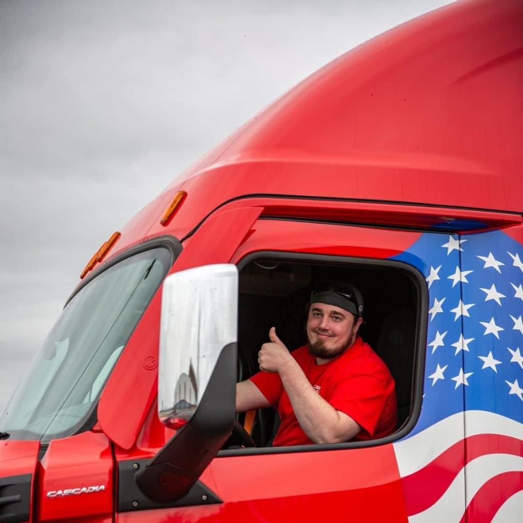 Happy truck driver giving a thumbs up from their driver seat.